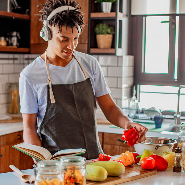 Culinary student listens to a podcast while prepping vegetables in his kitchen