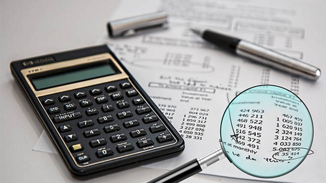 A tax calculator and magnifying glass, tools for precise financial calculations and analysis.