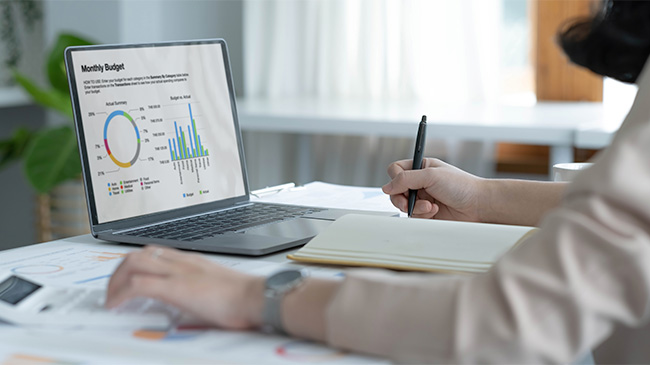 A person focused on their laptop, analyzing a graph displayed on the screen, while working diligently.