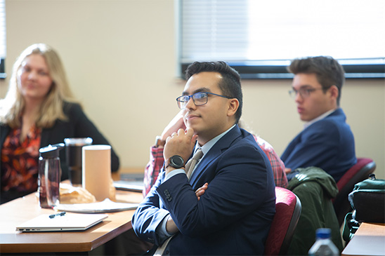 A student in formal attire sitting attentively in a classroom, ready to engage in learning.