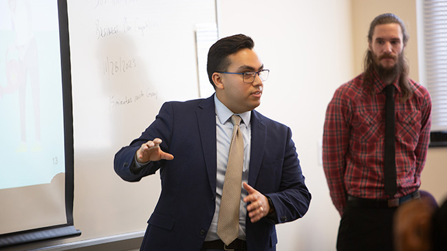 A student stands in front of a whiteboard, ready to deliver a presentation.