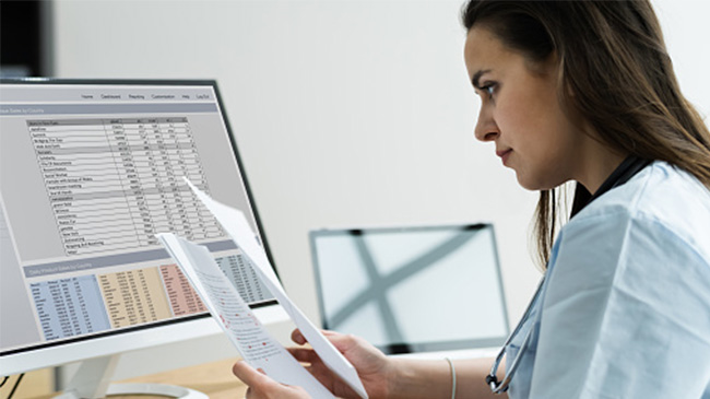 A woman in a lab coat analyzing data on a computer screen.