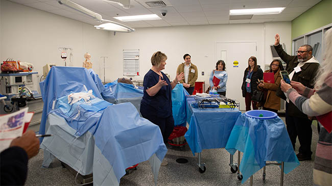 A surgical technologist carefully holds a pair of surgical scissors.