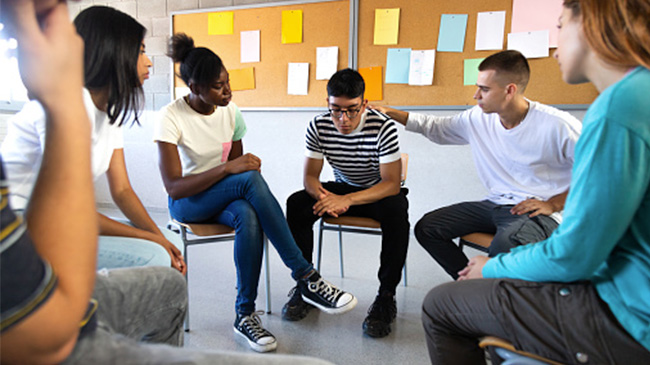 Young individuals sitting in a circle, interacting and sharing ideas.