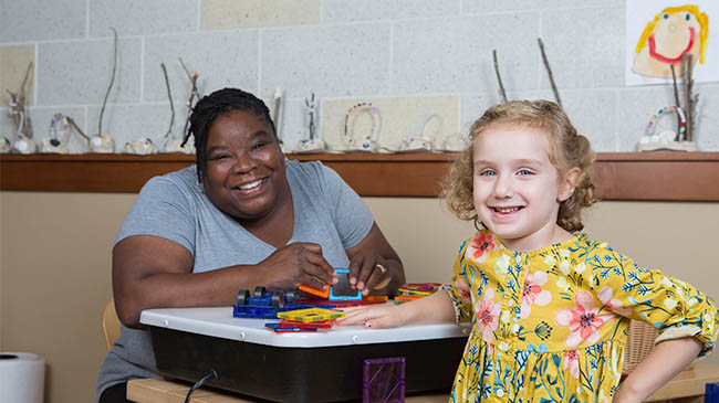  Woman and child sitting at table with toy.