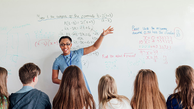 A teacher instructing a diverse group of students in a classroom setting.