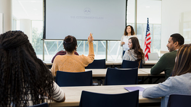 A teacher instructing a diverse group of students in a classroom setting.