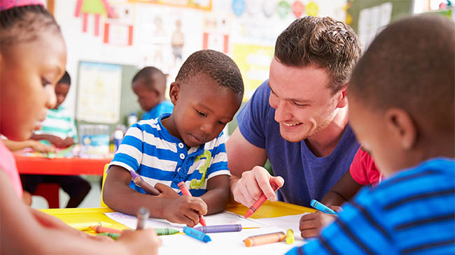 A woman and a boy sitting at a desk, engaged in an activity together.