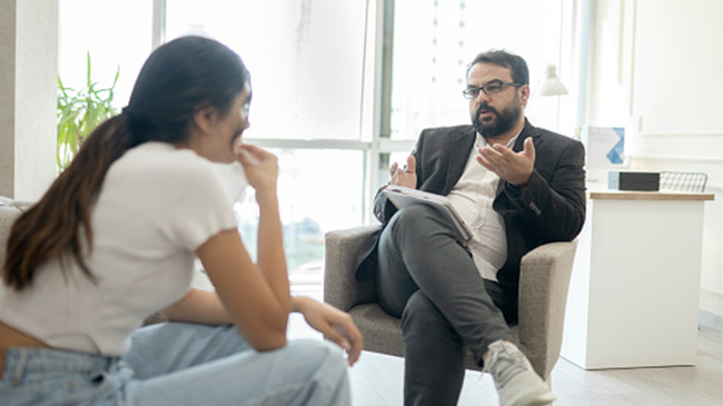 A man and woman engaged in conversation while seated on a chair.