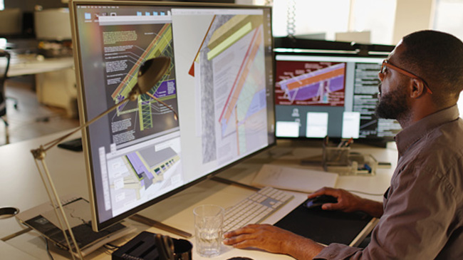 A man sitting at a desk, focused on a computer screen.